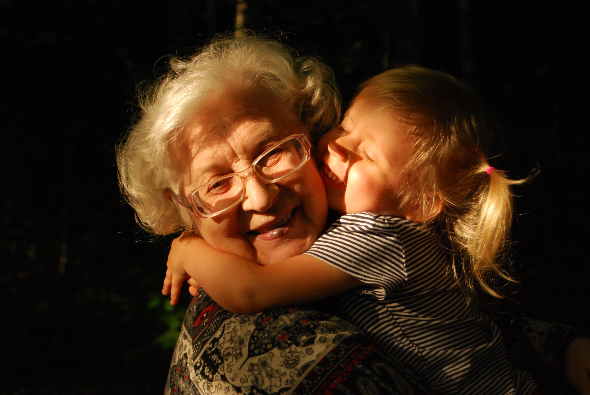 older woman being hugged by a young girl, representing a grandmother and her grandchild